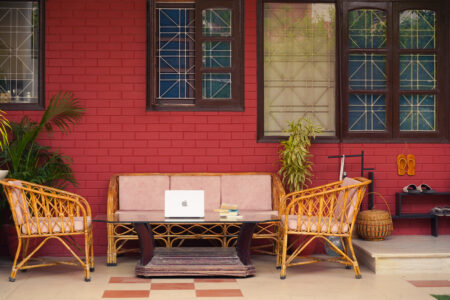 Covered porch with wicker seating, cushions, and potted plants