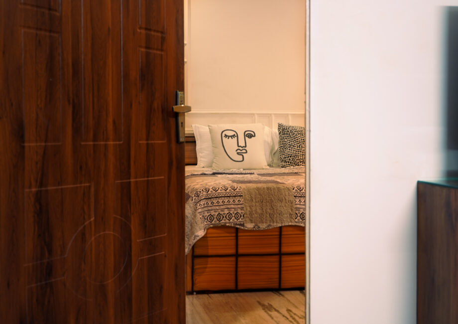 Inviting doorway view into the Ground Floor Haven with patterned linens and minimalist wall moulding.