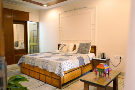 Ground Floor Haven bedroom with warm neutral décor, double bed, sofa, and garden-facing windows at The Basera Rishikesh.