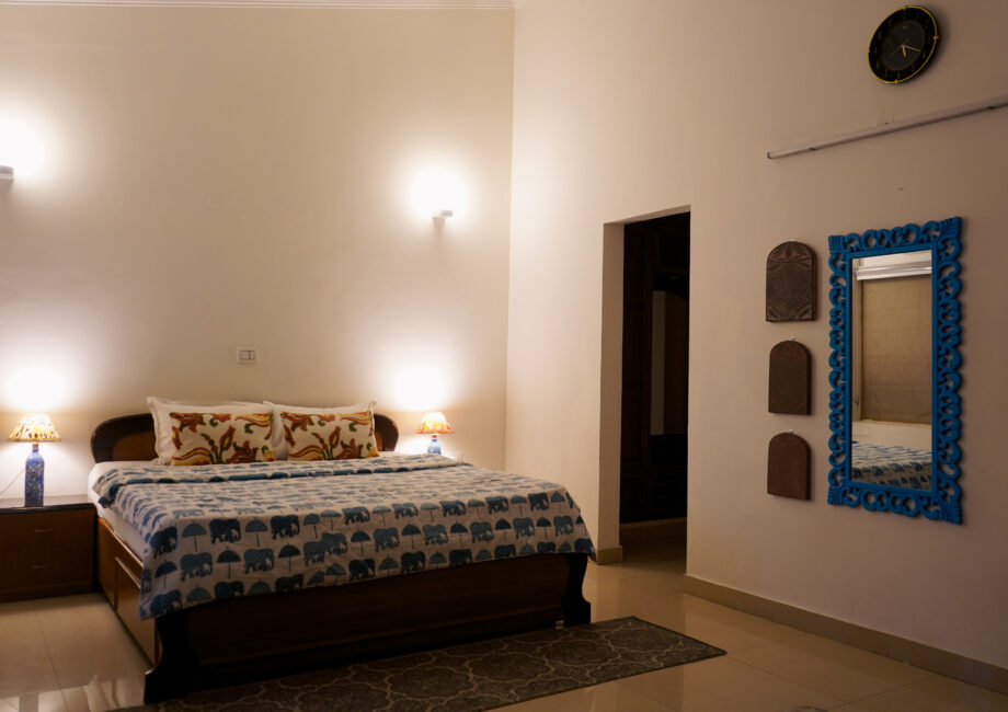 Full room view with king bed, blue framed mirror, and wall decor