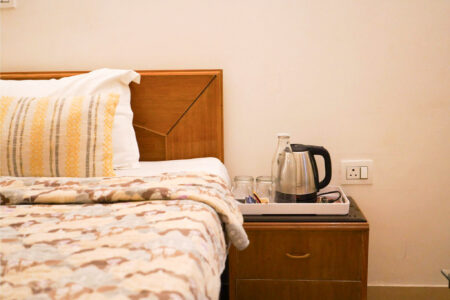 Bedside tray with kettle, glasses, and bottled water for guests