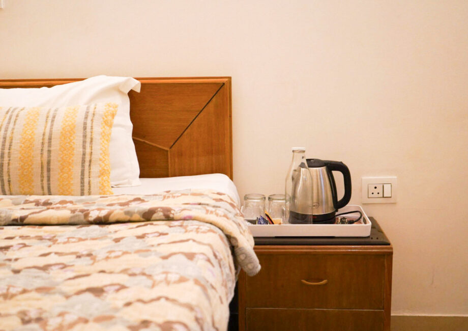 Bedside tray with kettle, glasses, and bottled water for guests