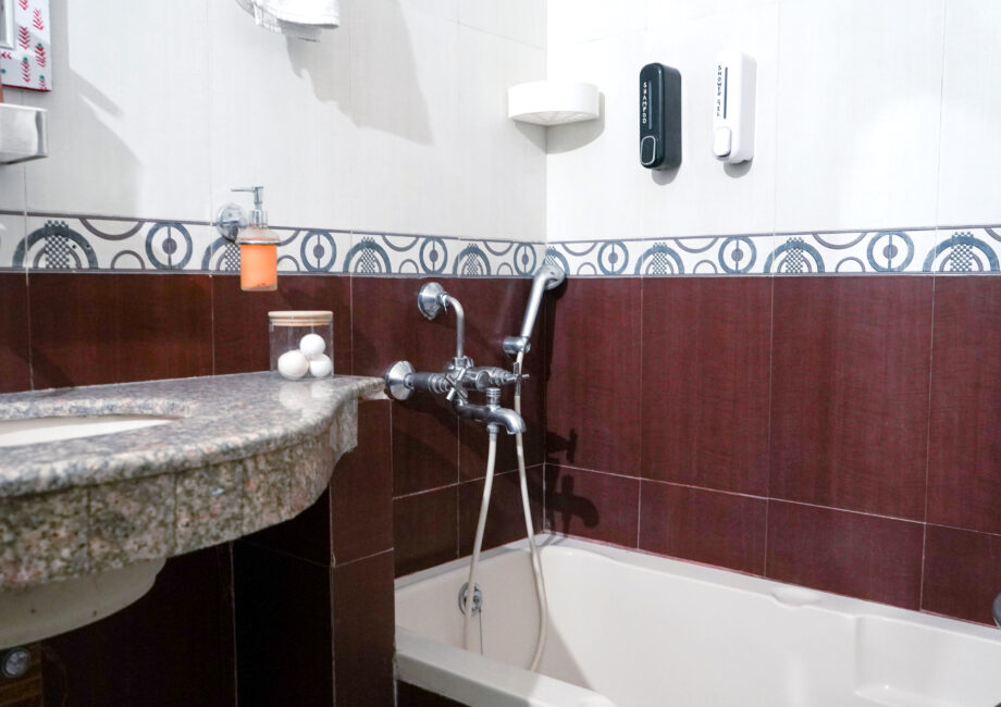 Bathtub with mixer tap and wall‑mounted shampoo/body wash dispensers