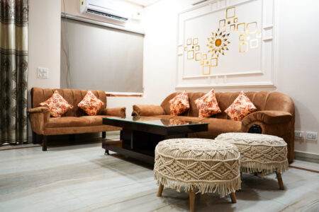 Shared living room with brown sofas, glass coffee table and macramé poufs