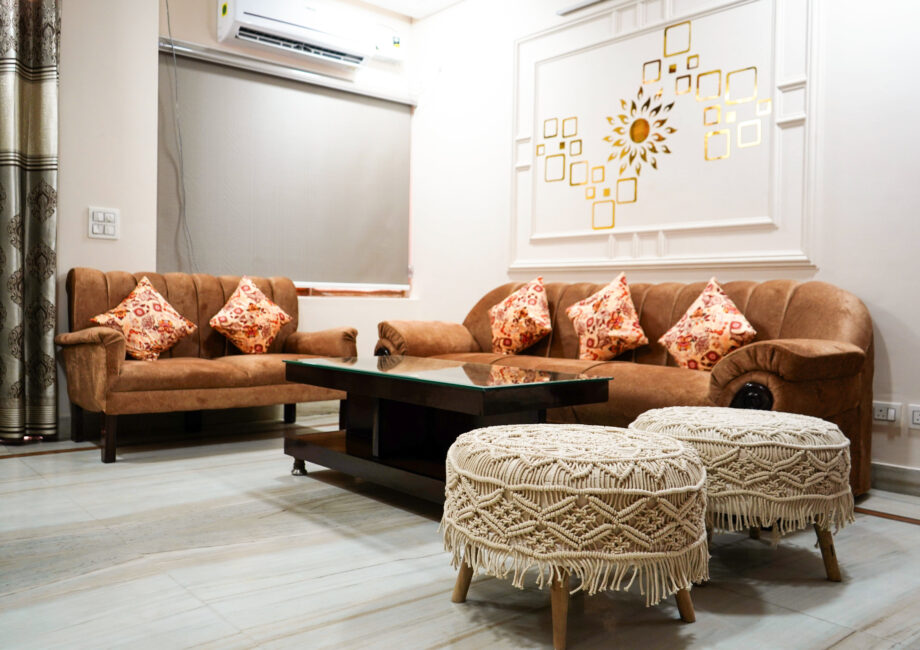 Shared living room with brown sofas, glass coffee table and macramé poufs