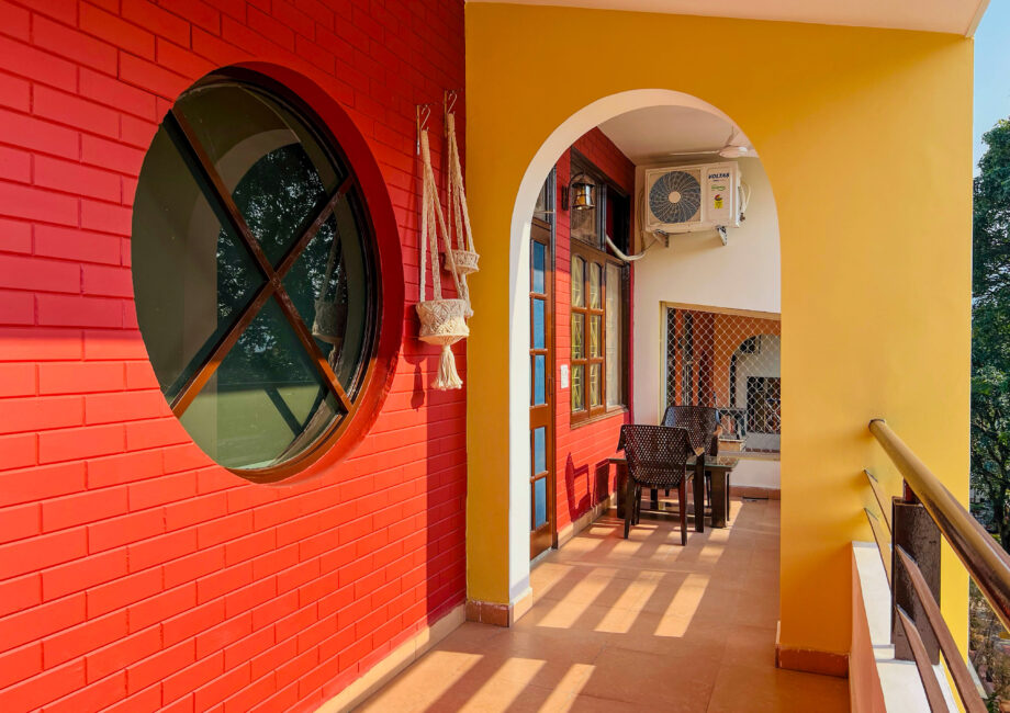 Balcony corridor close‑up with round window and macrame planters
