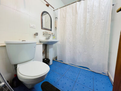Private bathroom with bath, shower curtain, pedestal basin and blue tiled floor Ground Floor Haven, Rishikesh.
