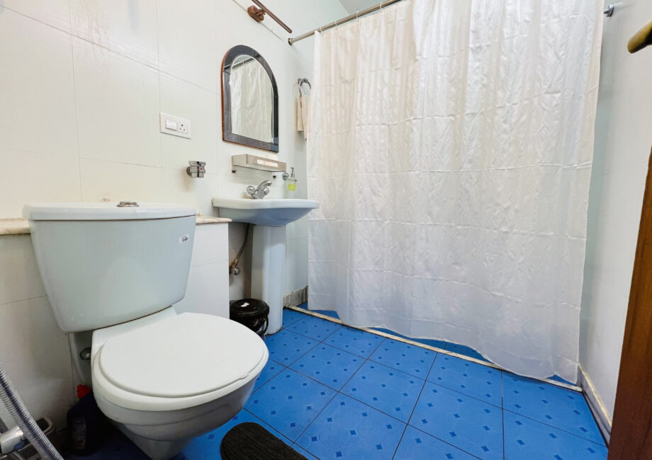 Private bathroom with bath, shower curtain, pedestal basin and blue tiled floor Ground Floor Haven, Rishikesh.