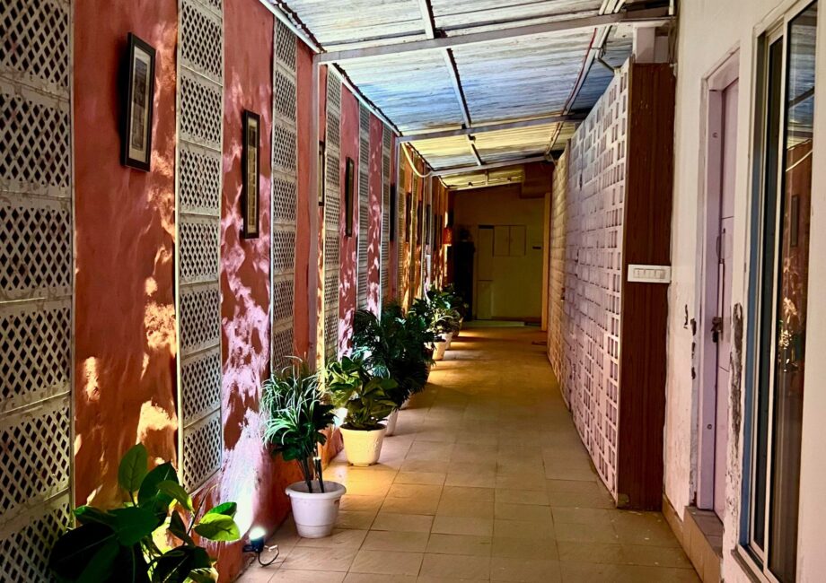 Ambient corridor with potted plants and lattice panels, warmly lit walkway at The Basera property.