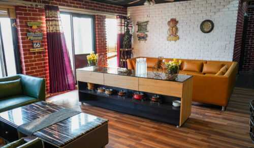 Spacious penthouse living lounge with sectional sofas, buffet console, brick walls, and large windows