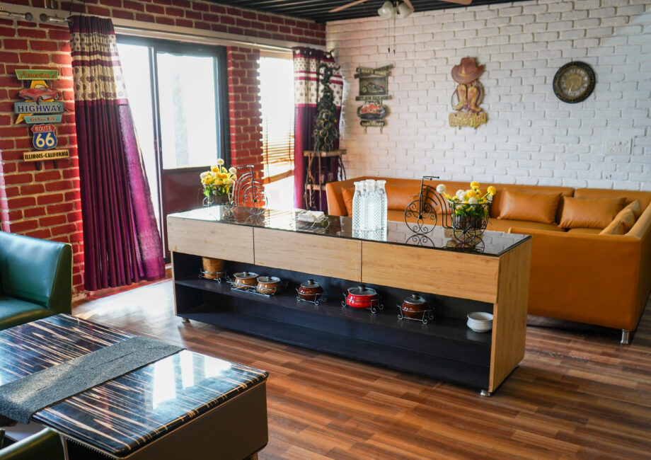 Spacious penthouse living lounge with sectional sofas, buffet console, brick walls, and large windows