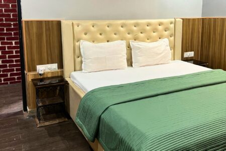 Beige tufted headboard and neatly made king bed with green quilt at The Basera penthouse.
