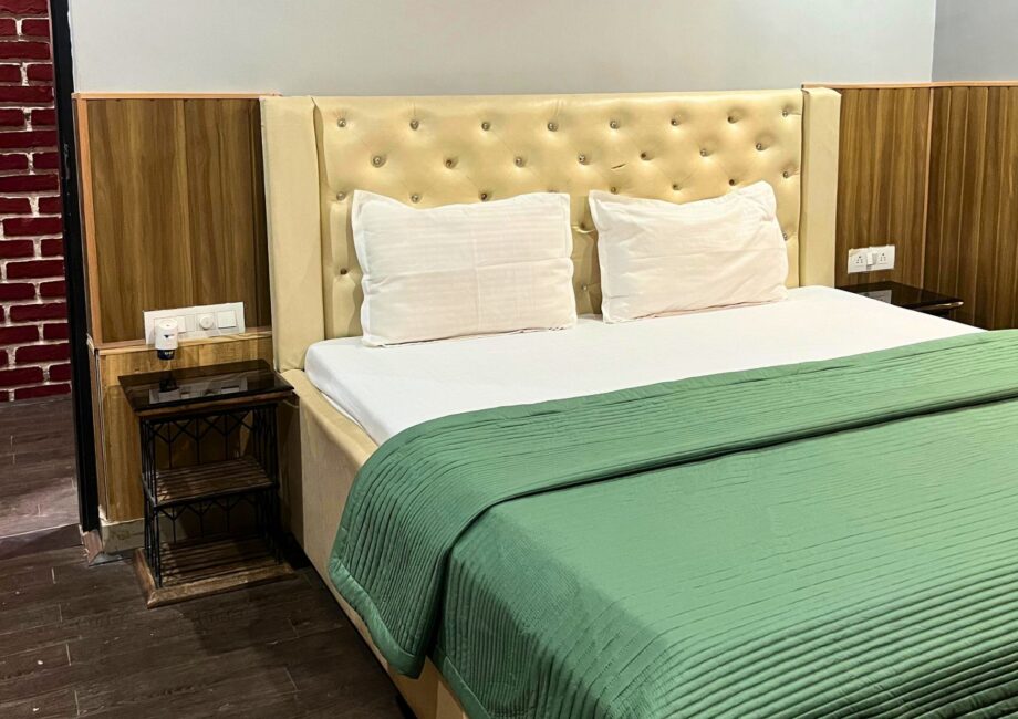 Beige tufted headboard and neatly made king bed with green quilt at The Basera penthouse.