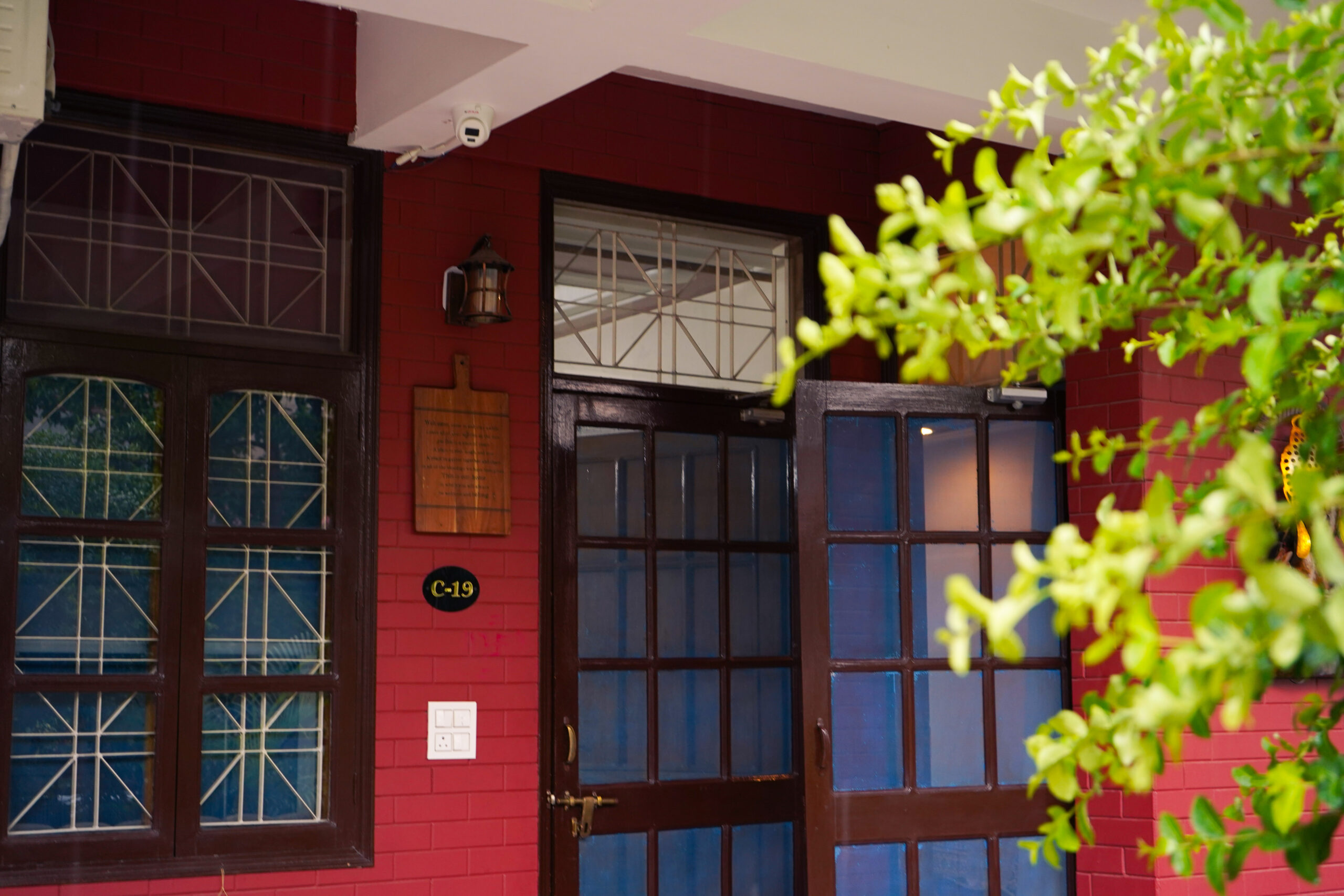 Front entrance of The Basera villa in Rishikesh with open wooden doors and security camera