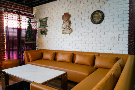 L-shaped tan sofa with marble coffee table against a white brick feature wall in the penthouse