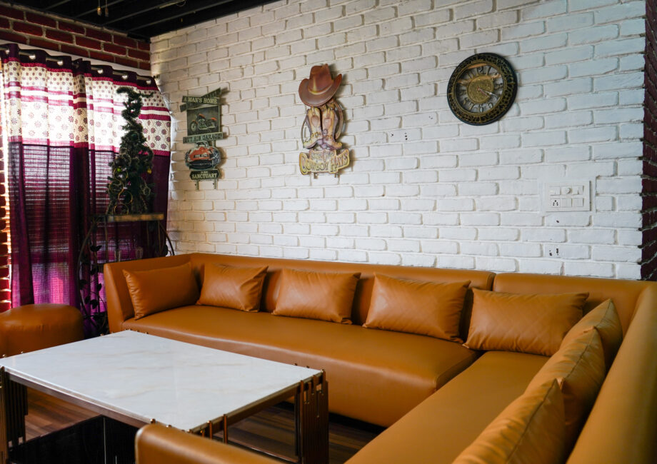 L-shaped tan sofa with marble coffee table against a white brick feature wall in the penthouse