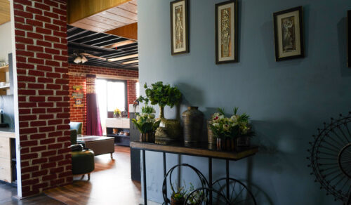 Decor corner with console table, vases, indoor plants, and exposed brick near the living area