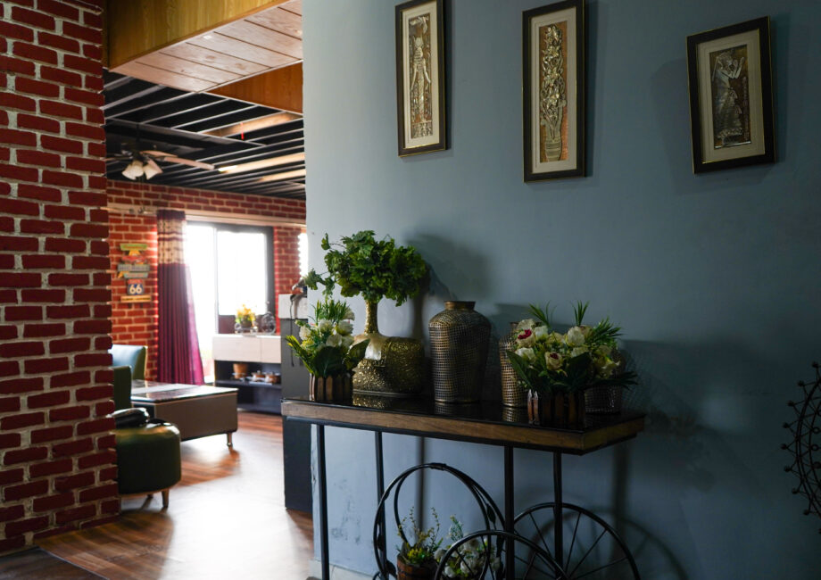 Decor corner with console table, vases, indoor plants, and exposed brick near the living area