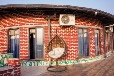 Wide curved terrace of the penthouse with multiple windows and a wicker egg swing chair