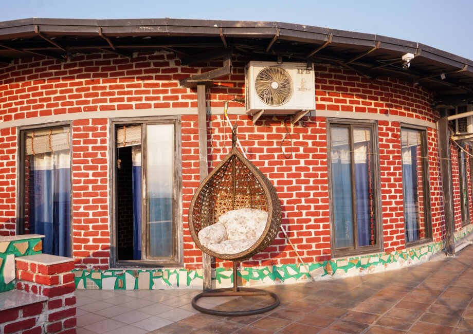 Wide curved terrace of the penthouse with multiple windows and a wicker egg swing chair