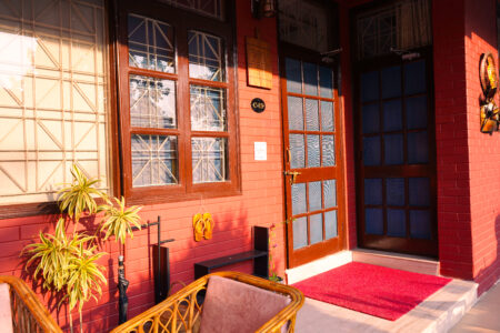 Warm-toned villa entrance at sunrise with cane seating and hanging wall decor outside The Basera