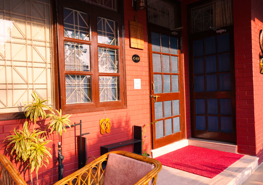 Warm-toned villa entrance at sunrise with cane seating and hanging wall decor outside The Basera
