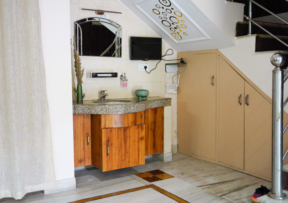 Compact washbasin and mirror setup under staircase at The Basera villa, blending functionality and design