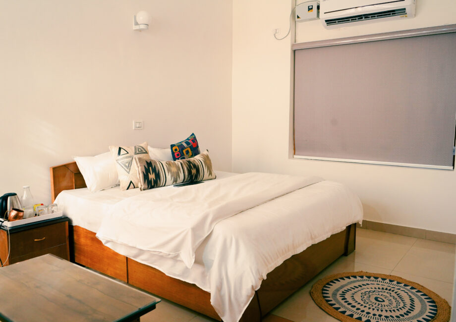 Minimalist bedroom with soft lighting, wooden furniture, and air conditioner in The Little Paradise.