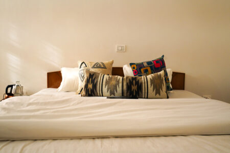 Neatly made bed with decorative pillows and bedside essentials in the mountain-view room.