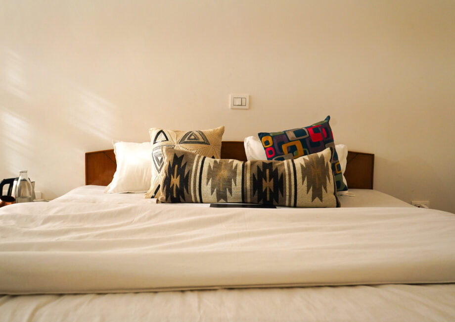 Neatly made bed with decorative pillows and bedside essentials in the mountain-view room.