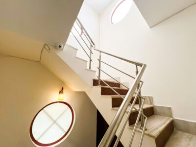 Bright indoor staircase with circular frosted glass window and clean railing in The Basera 4BHK villa