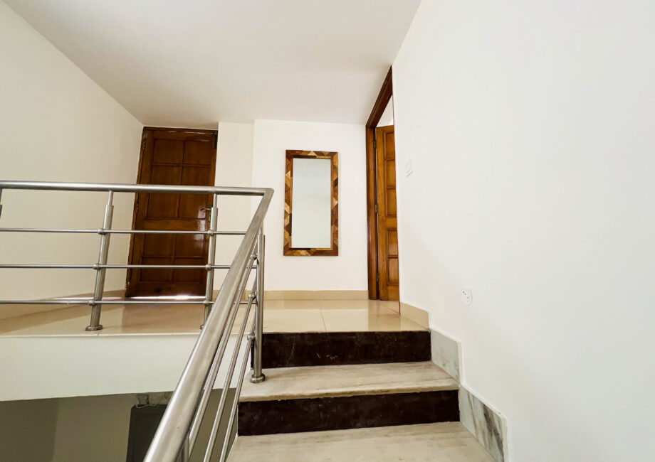 Spacious double bed with crisp white linens and tribal-print cushions at The Basera.